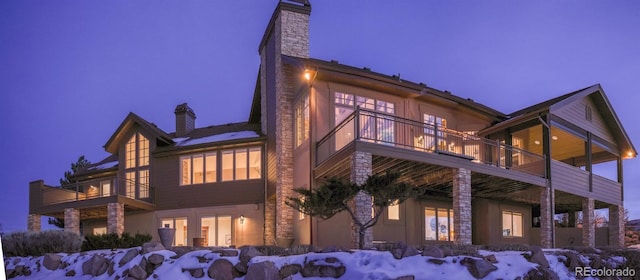 view of snow covered exterior featuring a balcony and a chimney