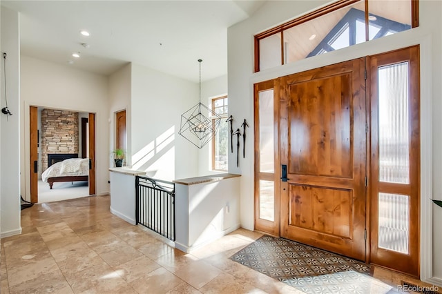 entryway with high vaulted ceiling, a fireplace, baseboards, and an inviting chandelier