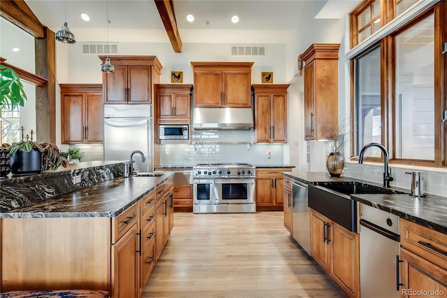 kitchen featuring built in appliances, a sink, visible vents, and under cabinet range hood