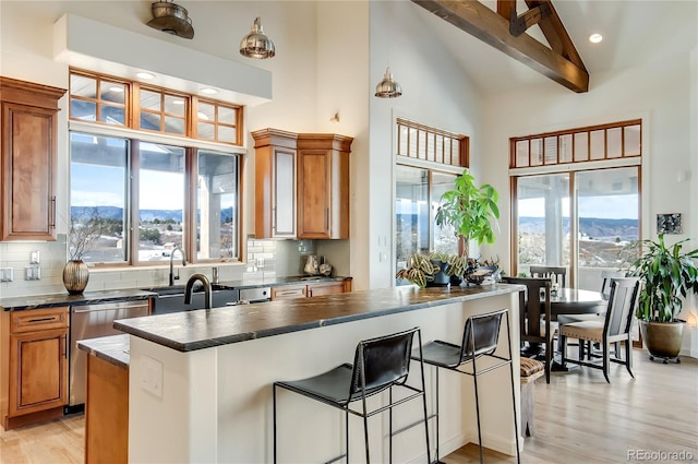 kitchen with light wood-style flooring, a mountain view, backsplash, brown cabinets, and dark countertops