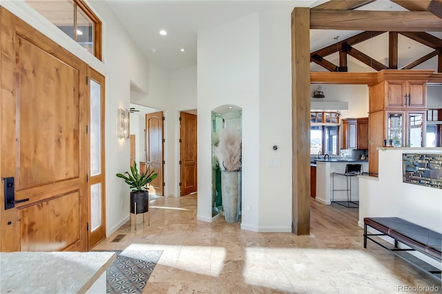 entrance foyer featuring arched walkways, high vaulted ceiling, visible vents, and baseboards