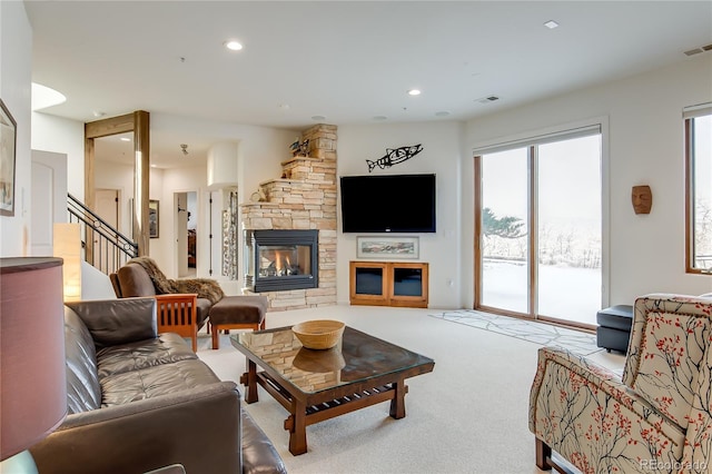 carpeted living area featuring recessed lighting, visible vents, a fireplace, and stairway