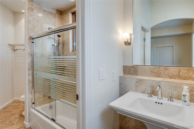 bathroom with shower / bath combination with glass door, a sink, toilet, and backsplash