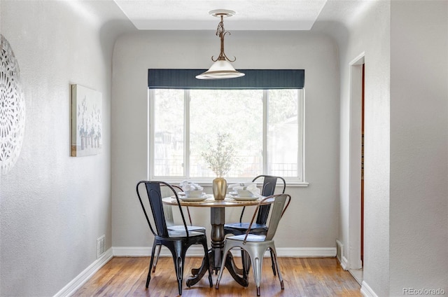 dining room featuring wood finished floors, baseboards, and a textured wall