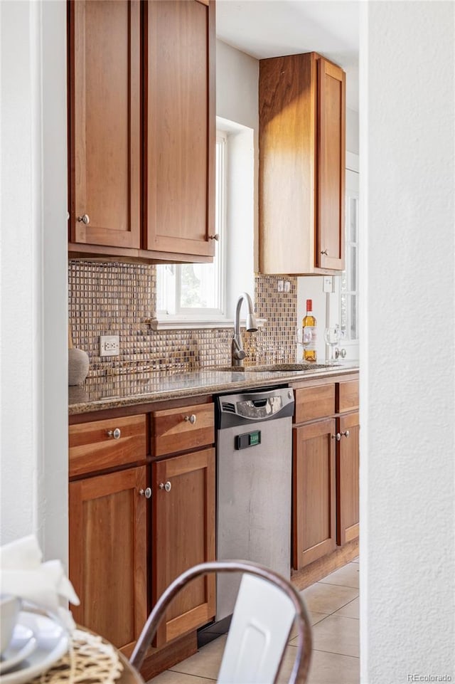 kitchen featuring dishwasher, a sink, tasteful backsplash, stone countertops, and brown cabinets