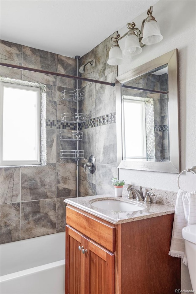 full bathroom with healthy amount of natural light, vanity, washtub / shower combination, and toilet