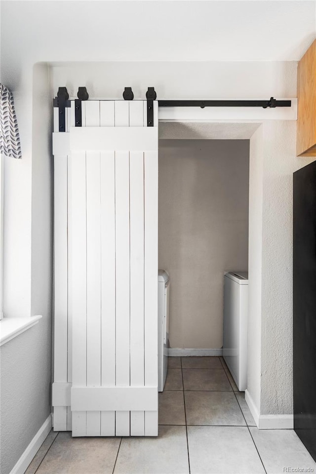 laundry room featuring tile patterned floors, a barn door, and baseboards