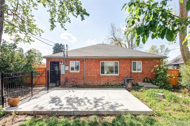 rear view of house featuring a patio area, brick siding, fence, and central air condition unit