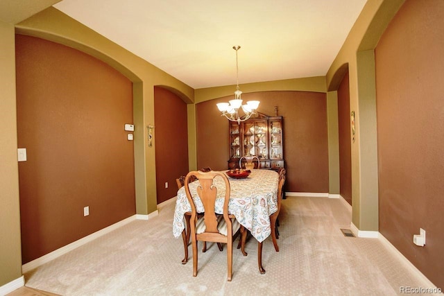 14200 W 86th Pl, Arvada, CO 80005 - dining room featuring arched walkways, a chandelier, light carpet, and baseboards