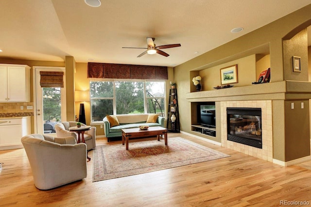 14200 W 86th Pl, Arvada, CO 80005 - living room featuring a tiled fireplace, a ceiling fan, light wood-style floors, and healthy amount of natural light