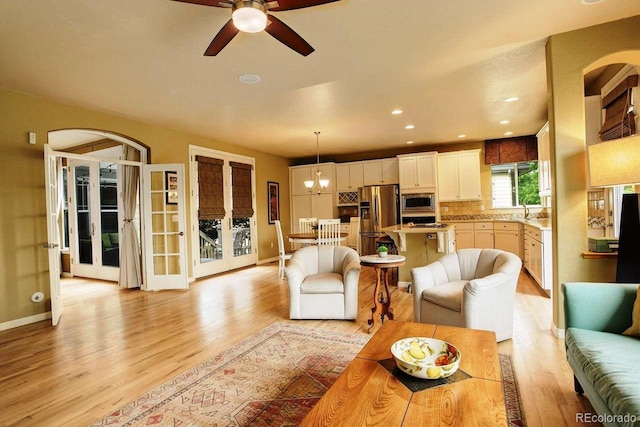 14200 W 86th Pl, Arvada, CO 80005 - living room featuring light wood-style flooring, a ceiling fan, baseboards, arched walkways, and french doors
