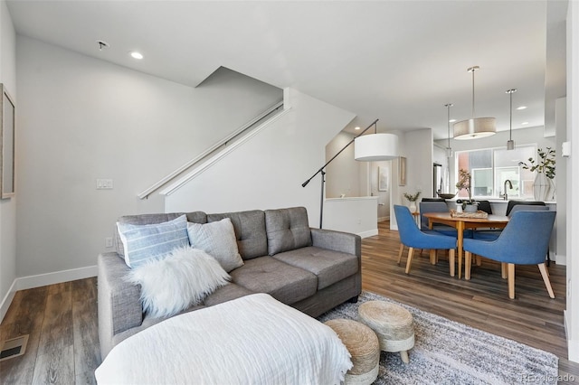 living area featuring stairway, wood finished floors, visible vents, and baseboards