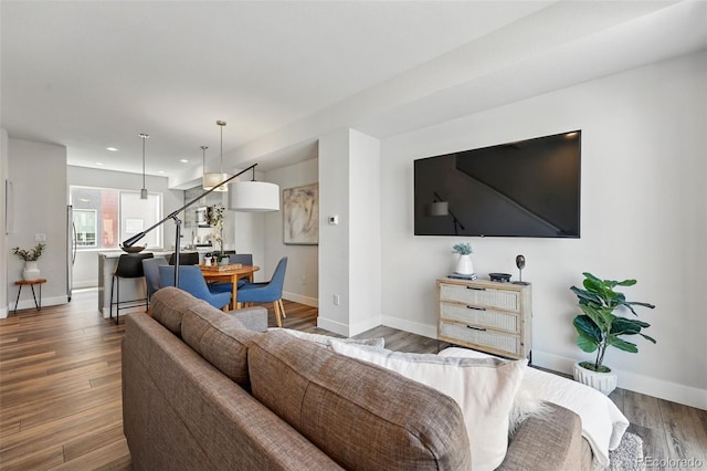 living room featuring recessed lighting, baseboards, dark wood-style floors, and stairs