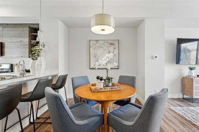 dining space with baseboards and wood finished floors