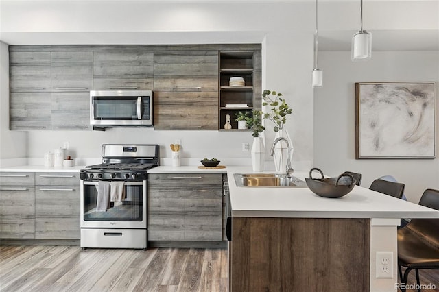 kitchen with a breakfast bar area, gray cabinets, a sink, appliances with stainless steel finishes, and modern cabinets