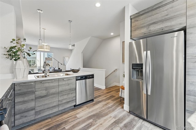 kitchen featuring modern cabinets, gray cabinetry, a sink, stainless steel appliances, and a peninsula