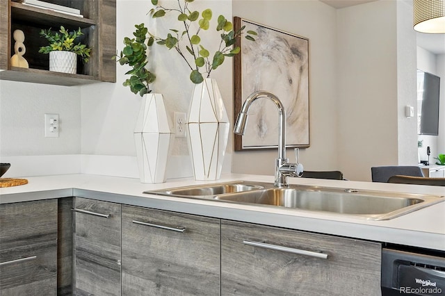 kitchen featuring dishwashing machine, gray cabinets, a sink, light countertops, and modern cabinets