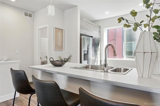 kitchen with a sink, visible vents, a kitchen bar, and stainless steel fridge with ice dispenser