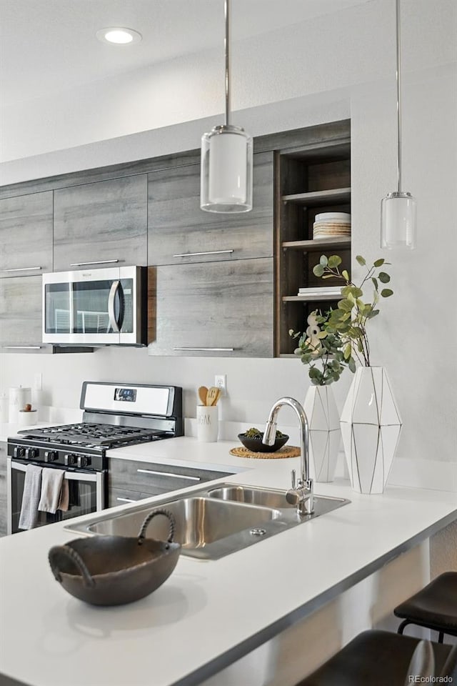 kitchen with light countertops, pendant lighting, appliances with stainless steel finishes, and a sink