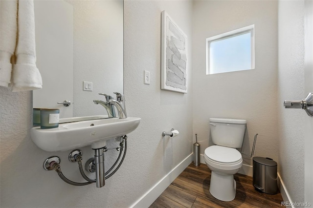 bathroom with a sink, baseboards, toilet, and wood finished floors