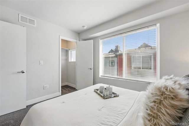 carpeted bedroom featuring a walk in closet, baseboards, and visible vents