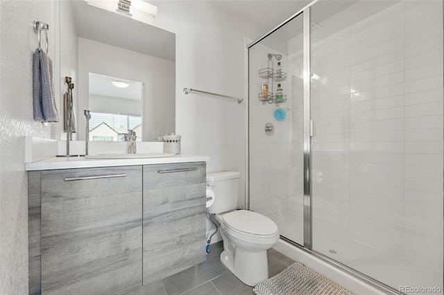 bathroom featuring tile patterned floors, a stall shower, toilet, and vanity