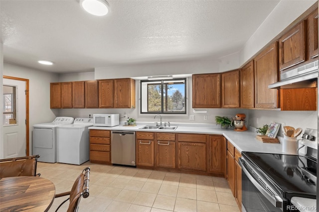 kitchen featuring independent washer and dryer, stainless steel appliances, light countertops, under cabinet range hood, and a sink