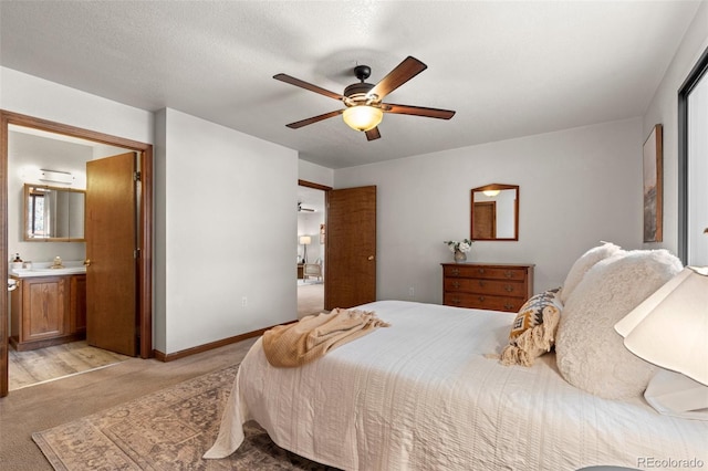 bedroom featuring a textured ceiling, light colored carpet, a ceiling fan, baseboards, and ensuite bath