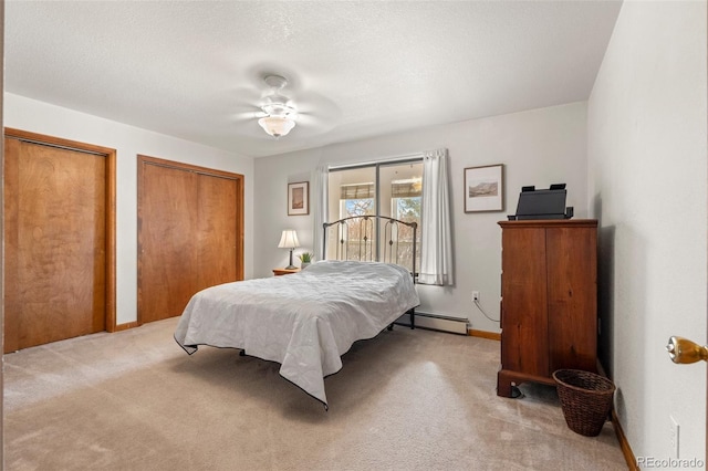 bedroom with baseboards, light colored carpet, a baseboard radiator, a textured ceiling, and multiple closets