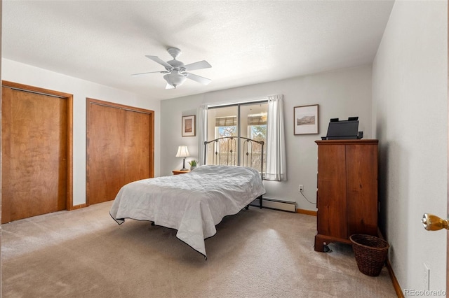 bedroom with two closets, baseboard heating, a ceiling fan, light carpet, and baseboards