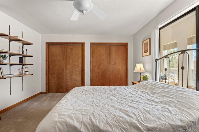 bedroom featuring a textured ceiling, carpet floors, a ceiling fan, baseboards, and multiple closets