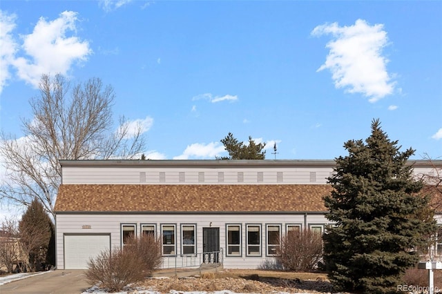 exterior space with a garage, concrete driveway, and a shingled roof