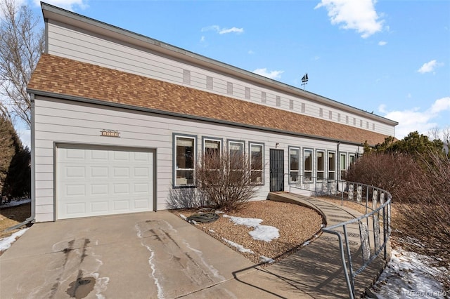 view of front of property with concrete driveway, roof with shingles, and an attached garage