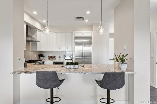 2500 E Cherry Creek S Drive 313, Denver, CO 80209 - kitchen with built in fridge, wall chimney range hood, a peninsula, tasteful backsplash, and a sink