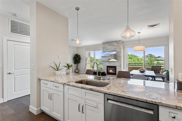 2500 E Cherry Creek S Drive 313, Denver, CO 80209 - kitchen featuring stainless steel dishwasher, a sink, a fireplace, white cabinets, and light stone counters