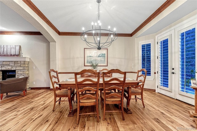 10459 Rivington Ct, Lone Tree, CO 80124 - dining space with light wood-style floors, crown molding, a chandelier, a stone fireplace, and arched walkways