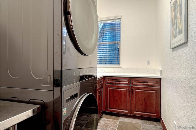 10459 Rivington Ct, Lone Tree, CO 80124 - laundry room with stacked washing machine and dryer, cabinet space, a textured wall, and light stone finish floors