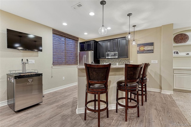10459 Rivington Ct, Lone Tree, CO 80124 - kitchen featuring appliances with stainless steel finishes, a kitchen breakfast bar, light wood-style floors, light countertops, and hanging light fixtures