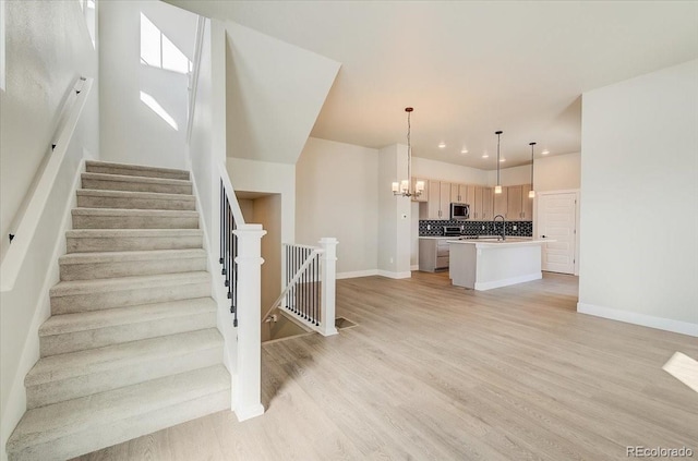 stairway featuring a chandelier, wood finished floors, baseboards, and recessed lighting