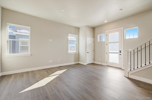 foyer entrance with wood finished floors, baseboards, stairway, and recessed lighting