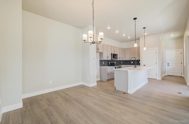 kitchen with stainless steel appliances, a chandelier, decorative backsplash, light wood-type flooring, and a sink