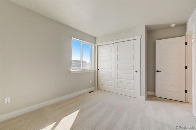 unfurnished bedroom featuring light carpet, a closet, and baseboards