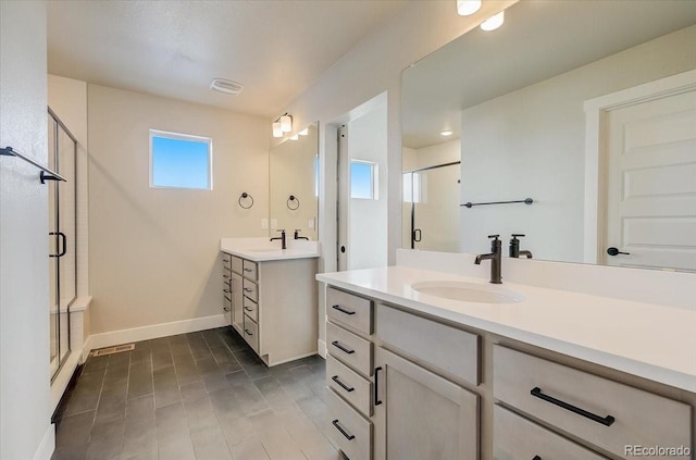 bathroom with a shower stall, two vanities, and baseboards