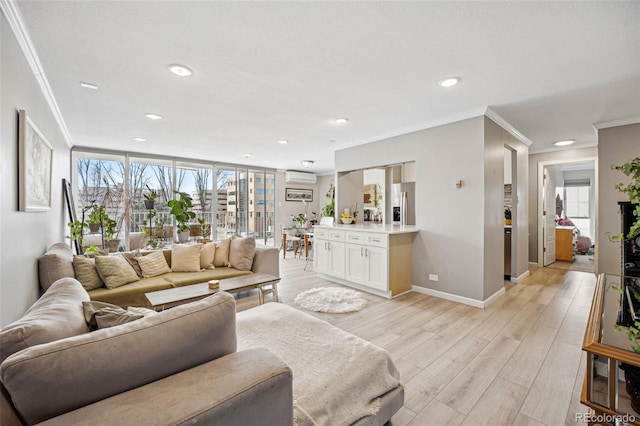 living room with crown molding, a healthy amount of sunlight, a wall mounted air conditioner, and light wood-style floors