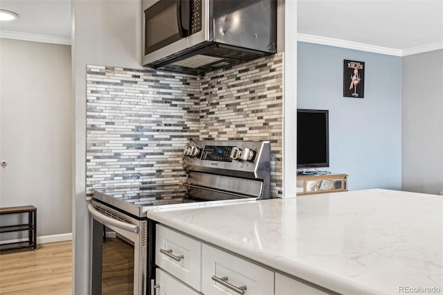 kitchen with stainless steel appliances, white cabinets, backsplash, light stone countertops, and crown molding