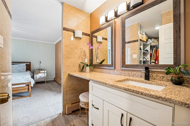 bathroom featuring wood finished floors, ensuite bathroom, crown molding, vanity, and a baseboard heating unit