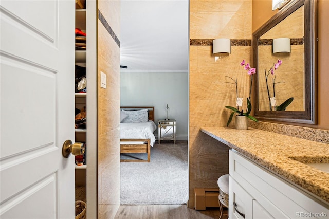 bathroom featuring ensuite bathroom, ornamental molding, wood finished floors, and vanity