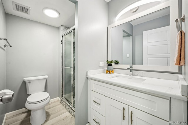 bathroom featuring visible vents, toilet, a stall shower, vanity, and wood finished floors