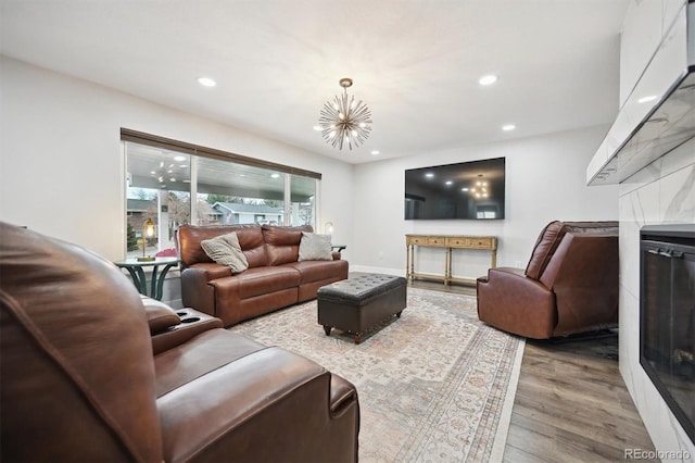 living room featuring a notable chandelier, light hardwood / wood-style flooring, and a tile fireplace