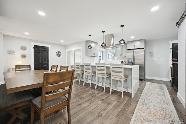 dining area with sink, a barn door, and wood-type flooring